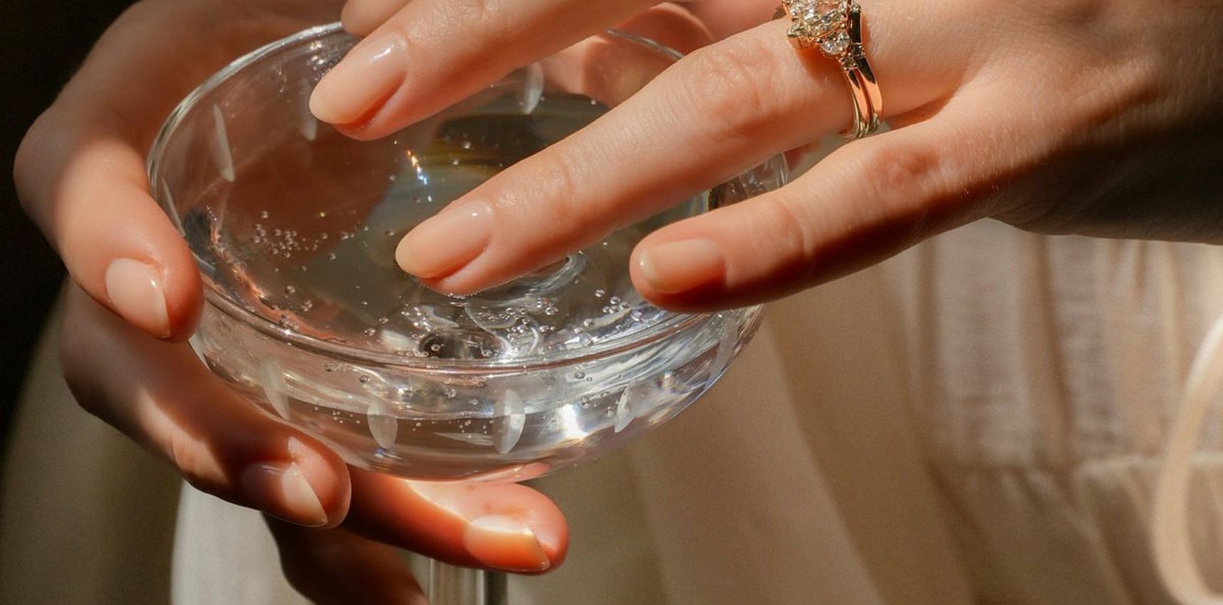 Hand holding glass bowl, nail care ritual